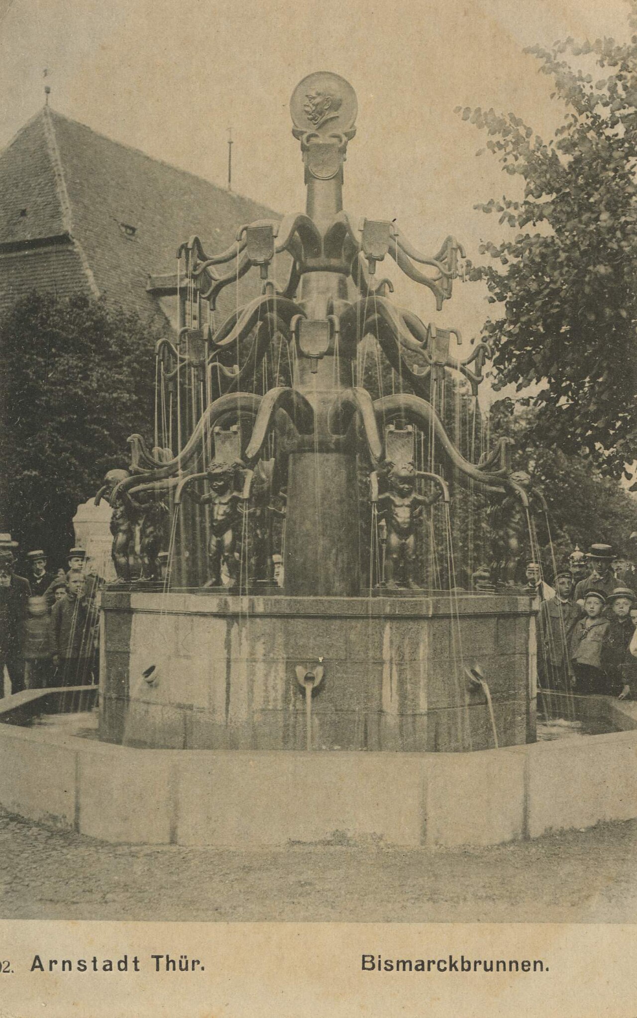 Historische Ansichtskarte des Bismarckbrunnens mit Menschen auf dem Platz.